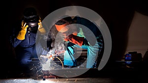 Workers in safety clothing welding steel parts in industrial