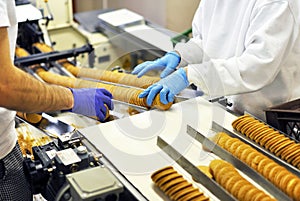 Workers sort biscuits on a conveyor belt in a factory - producti