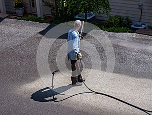 Workers spraying blacktop or asphalt sealer onto roadway