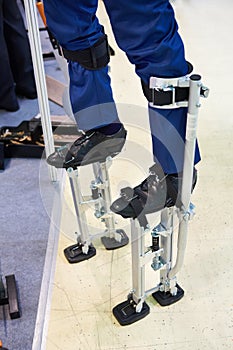 Workers stilts wearing on legs of men