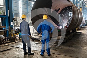 Workers supervising the manufacture of a metallic cylinder