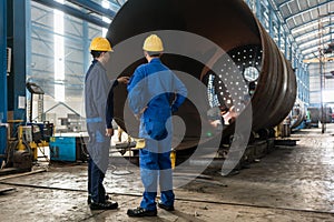 Workers supervising the manufacture of a metallic cylinder