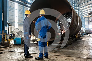 Workers supervising the manufacture of a metallic cylinder photo