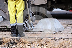 workers trying to load a concrete stand on road sign in the excavator bucket during repair work the