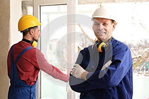 Workers in uniform installing plastic window