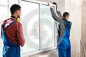 Workers in uniform installing plastic window