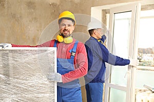 Workers in uniform installing plastic windows