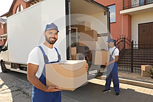 Workers unloading boxes from van outdoors. Moving service