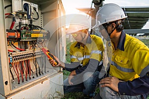 Workers use clamp meter to measure the current of electrical wires produced from solar energy for confirm to normal current