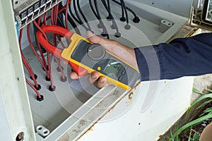 Workers use Clamp meter to measure the current of electrical wires produced from solar energy for confirm to systems working