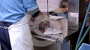 workers use an electric saw to cut frozen tuna into smaller portions at tsukiji fish market in tokyo