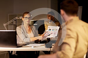 Workers with user interface mockup at night office