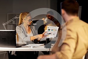 Workers with user interface mockup at night office