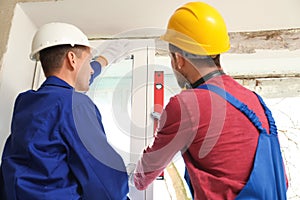 Workers using bubble level for installing window