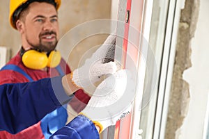 Workers using bubble level for installing window, closeup