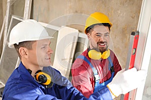 Workers using bubble level for installing window