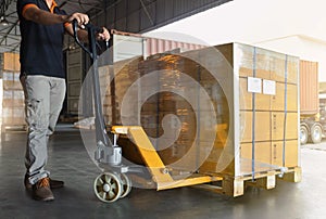 Workers Using Hand Pallet Jack Unloading Package Boxes into Cargo Container Delivery Shipment Boxes. Trucks Loading Dock Warehouse