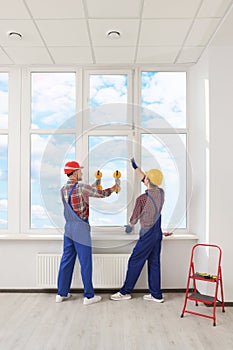 Workers using suction lifters during plastic window installation indoors photo
