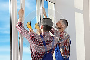 Workers using suction lifters during plastic window installation indoors photo