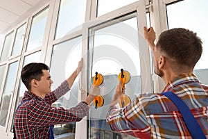 Workers using suction lifters during plastic window installation photo