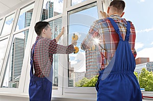 Workers using suction lifters during plastic window installation indoors photo