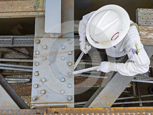 Workers are using a wrench to torque bolts to hold the splice plate to the steel beam of steel structure work