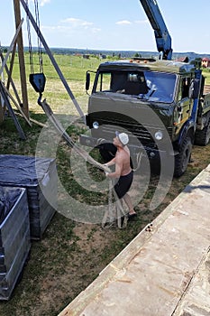 Workers in the village unload pallets with a front brick for construction with the help of a mobile crane