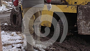 Workers walking in front of forklift stucked in deep mud