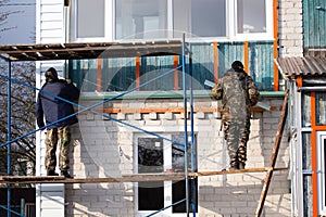 Workers walling the house with wall siding