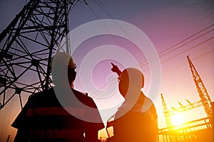 workers watching the power tower and substation with sunset b