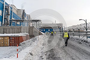 Workers wearing helmets and reflective vests go to the gold refinery.