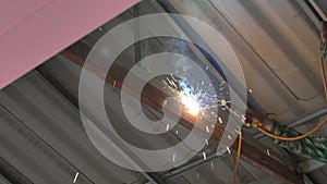 Workers weld steel structure with electric welding machines in factory,
