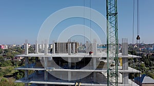 Workers work with crane and steel concrete reinforcement at large construction site of modern building. Modern