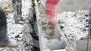 Workers work on site. Detail of casting pump concrete to foundations of family house
