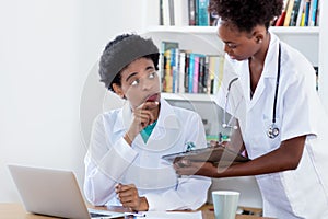 Working african american female doctor with young nurse or medical student