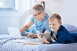 Pre-teen boy doing math homework while his father working