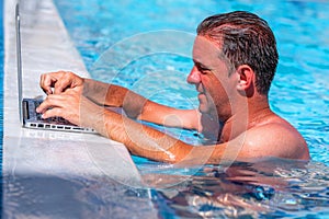 Working any time and anywhere. Businessman works remotely with  laptop computer on vacation in the swimming pool