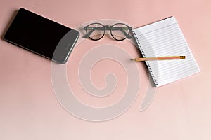 Pens, glasses and notebooks are on a pink background. photo