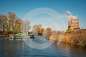 A working boat on the lake against the background of two cooling towers. Ecology, production and nature