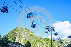 Working cable car chairs with visitors among green hills