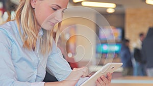 Working at the cafe. Young beautiful long hair woman sitting at the table and using tablet.