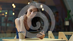 Working at the cafe. Young beautiful long hair woman sitting at the table and using tablet computer in outdoor cafe