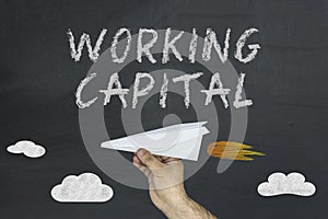 Working Capital concept with flying paper plane on blackboard