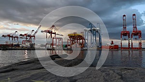 Working cargo ship yard on sunset. Global shipping container port - cranes loading cargo ship. Industrial place
