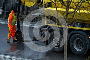 Working channel digger, doing the work at a open manhole ona wet street at the back of the channel cleaning vehicle.