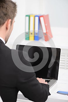 Working on the computer. Rear view of businessman in formalwear photo