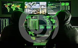 Hackers working on computers showing world maps and security camera footage