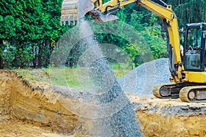 Working on a construction excavator moving gravel stones for foundation building