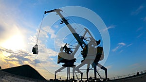 Working cranes carry rubbles in buckets while unloading them.