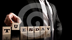 Working day - Businessman Arranging Small Wooden Blocks with word Tuesday